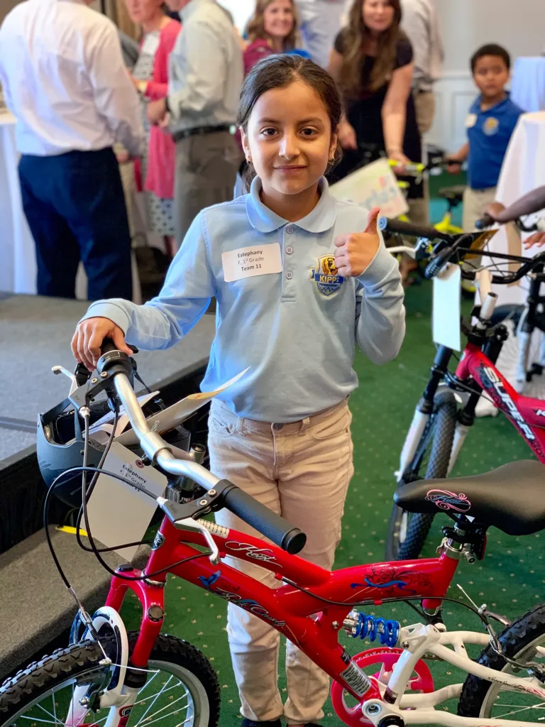 A girl gives a thumbs up after receiving a new bike